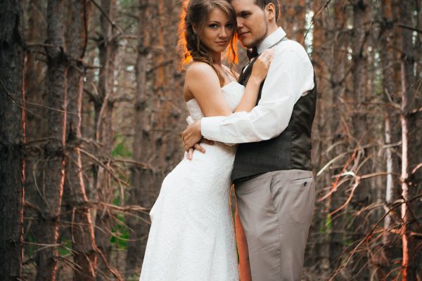 dramatic picture bride and groom on the background of leaves and forest backlight.
